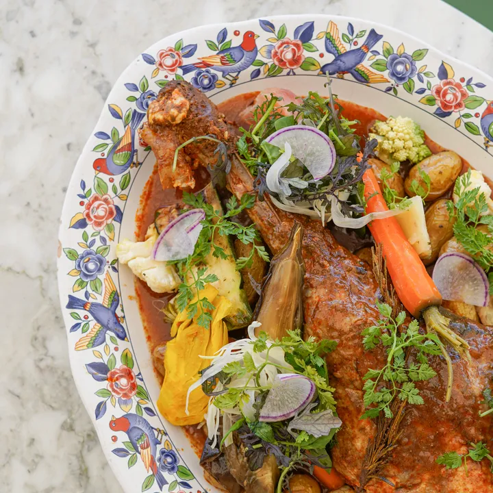 Un plat d'agneau confit, servi avec des légumes rôtis et une sauce au jus de viande