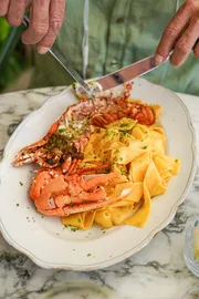 Un plat de pâtes au homard, avec une sauce tomate et des herbes fraîches